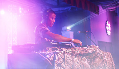 Focused DJ mixing tracks on a Pioneer DJ setup at a live club event with vibrant stage lighting