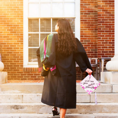 Graduate walking up the steps at Texas Women's University building