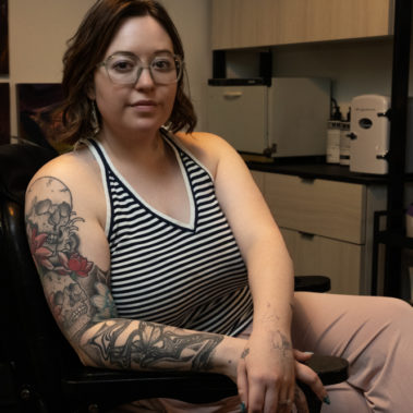 Hairstylist sitting in barber's chair with a full sleeve of tattoos